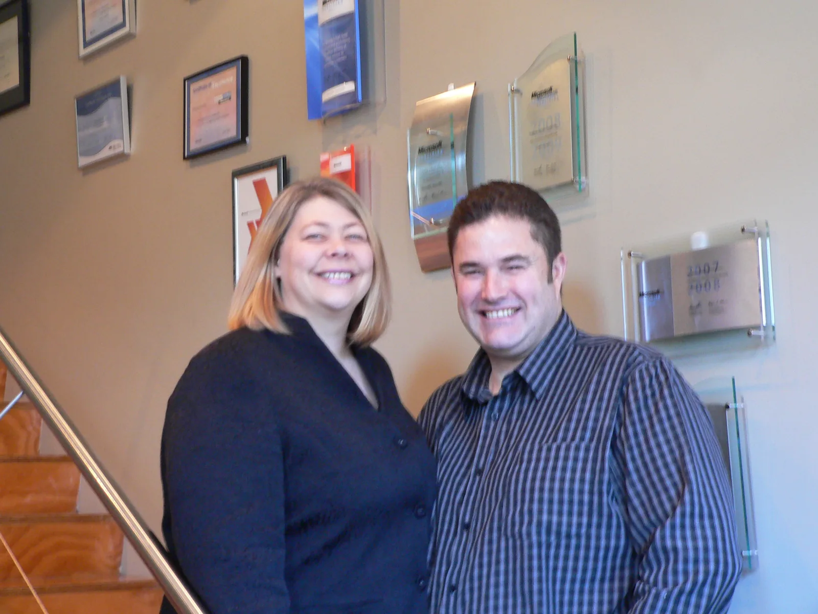 Mark and Victoria, founders of Decision1 IT Solutions, in front of the awards wall